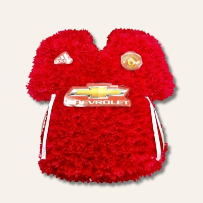 Manchester United shirt funeral tribute with fresh flower base, pipework detailing and printed waterproof badges, 21 x 21 inches, available in classic and modern shirt versions.